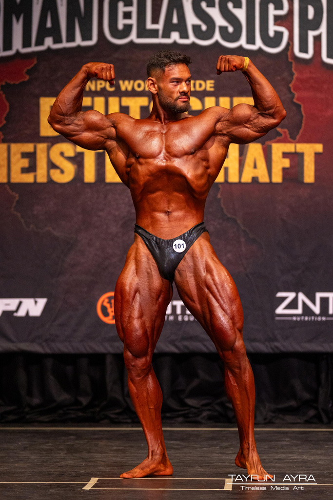 Coach posiert bei einem Bodybuilding-Wettbewerb.